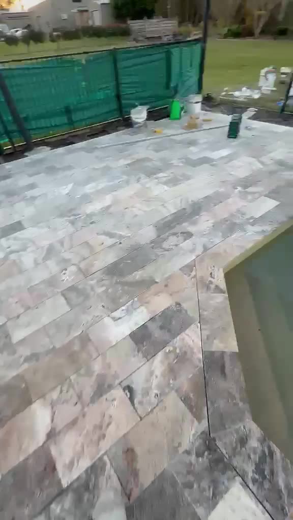 Travertine pool coping and paving around a freeform pool